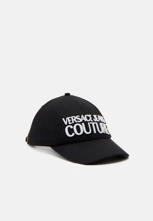 Zwarte baseballpet met wit geborduurde tekst "VERSACE JEANS COUTURE" op het voorpaneel.