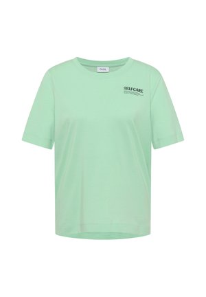 Mintgrøn t-shirt med korte ærmer og rund hals med teksten "SELFCARE" trykt i små sorte bogstaver på øverste venstre del af brystet.