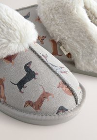 Hausschuhe mit Kunstfellfutter und weichem grauem Wildleder außen, verziert mit einem Dackelmuster in verschiedenen Farben, detaillierten Nähten und flachen Sohlen.