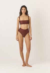 Bikini set v spálenej oranžovej farbe s textúrovaným povrchom. Vrchná časť má široké ramienka a obdĺžnikový strih; nohavičky s vysokým pásom dopĺňajú tento štýl.