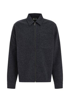 Chaqueta de cremallera en gris oscuro, fabricada con un tejido texturizado, que presenta un cuello puntiagudo y un solo bolsillo en el pecho. Mangas largas con puños ajustados.