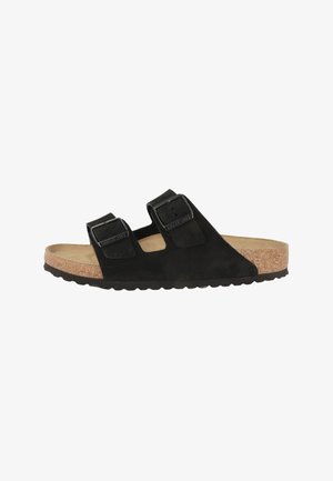 Black suede two-strap sandal with adjustable buckles and cork footbed, side view on white background.