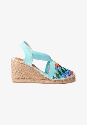 Kalde espadrillid, millel on piparmündiroheline kangas ja mitmevärviline tikitud zikk-zakk muster. Jutist põhi. Seljalukkudega disain koos ristatud rihmadega.