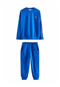 Set de bluză albastră și pantaloni asortați. Bluza are o broderie cu curcubeu și dungi colorate; pantalonii au buzunare laterale și talie elastică.