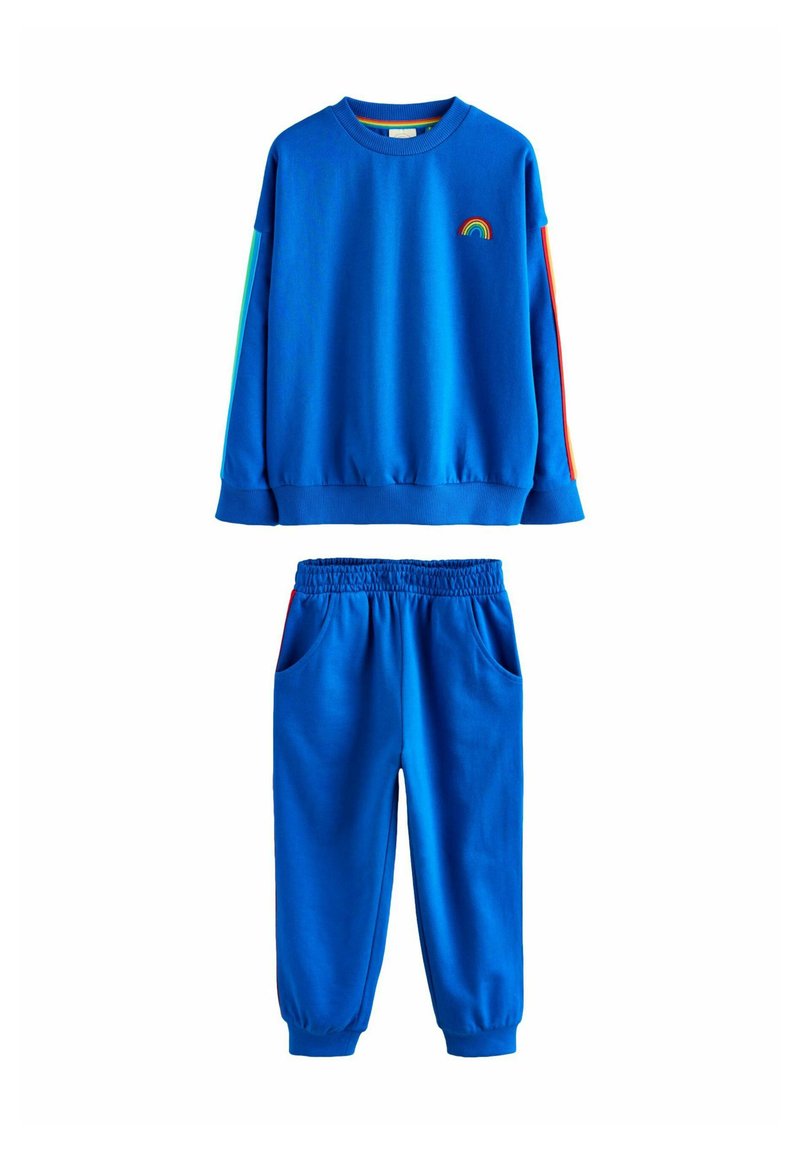 Set de bluză albastră și pantaloni asortați. Bluza are o broderie cu curcubeu și dungi colorate; pantalonii au buzunare laterale și talie elastică.