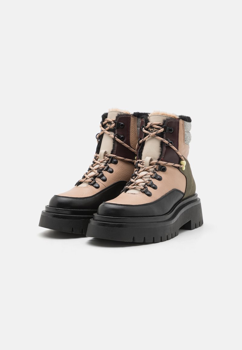 Stivali in una combinazione di pelle beige, marrone e nera con una suola in gomma spessa, occhielli in metallo e dettagli tessili decorati al collo.