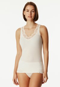 White, ribbed tank top with a deep V-neck and lace trim at the neckline. Smooth texture with a fitted design and narrow shoulder straps.
