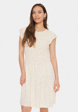 Blumengemustertes Midikleid in hellem Creme mit gerafftem Oberteil und kurzen Ärmeln. Weicher Stoff mit bunten kleinen Blumen überall.