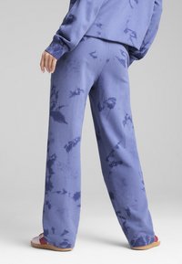 Purpursarkans tie-dye sporta bikses, izgatavotas no mīkstas auduma, ar brīvu piegriezumu un platām kājām. Akcenti ietver smalku rakstu tumšākos toņos.