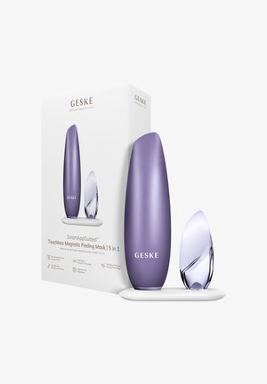Appareil et applicateur pour masque peeling magnétique sans contact Purple GESKE SmartAppGuided sur un support blanc à côté de la boîte du produit.