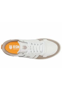 Valkoiset lenkkarit, joissa on vaaleanruskeita yksityiskohtia, joissa on texturoitu muotoilu, pyöreä varvas, nauhat ja oranssi pohjallinen, jossa lukee "K-SWISS COURT STYLE."