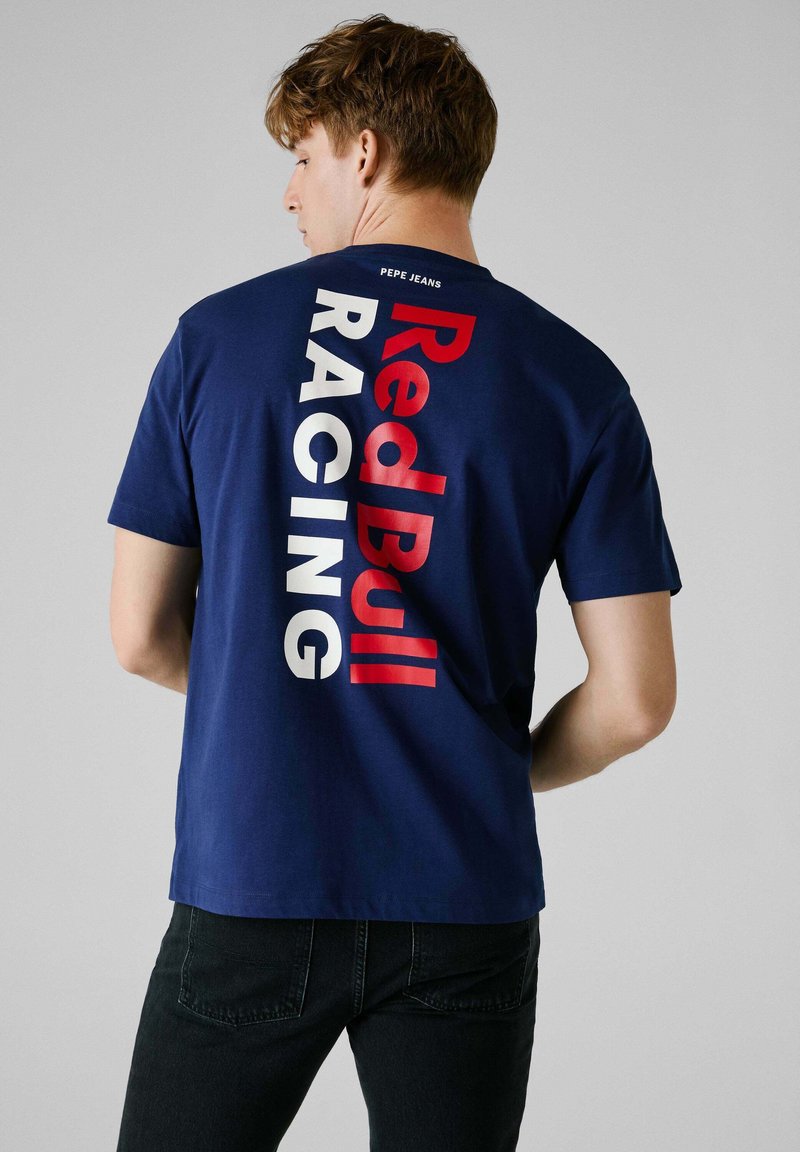 Granatowa bawełniana koszulka z krótkim rękawem, z odważnym pionowym nadrukiem "Red Bull Racing" w kolorze czerwonym i białym z tyłu. Okrągły dekolt.