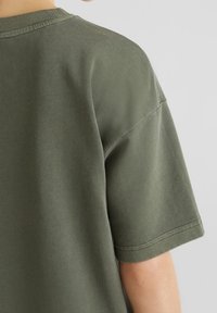 Short-sleeve olive green t-shirt with a relaxed fit, ribbed crew neckline, and smooth cotton texture; seams are neatly finished.