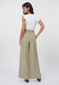 Hvit topp med volangerm  og khaki vide bukser med elastisk liv. Glatt tekstur, avslappet design og sidelommer.