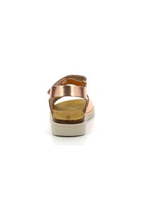 Sanda de color oro rosa metálico con una correa trasera, talón abierto, plantilla de corcho y suela de goma blanca, que muestra un diseño y textura minimalistas.