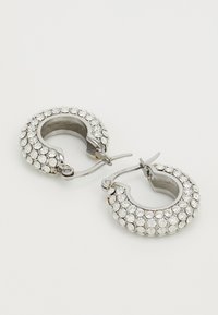 Strieborné kruhové náušnice osadené trblietavými priehľadnými rhinestones, s pántovým uzáverom a hladkým, lesklým povrchom.