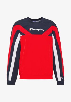 Sweat-shirt Champion manches longues rouge, marine et blanc avec logo sur la poitrine et un petit logo sur le bord de la manche gauche.
