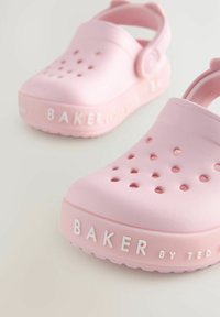 Rozā gumijas klumpi ar ventilācijas caurumiem, paceltu papēža siksniņu un iegravētu "BAKER by TED" logotipu sānos. Gluda tekstūra.