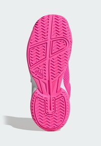 Podešev boty z jasně růžové gumy s texturovanými vzory ve tvaru cik-cak. Na patě je hladká bílá část a detail s logem značky.