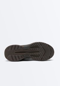 Sohle eines dunkelbraunen Sneakers mit strukturiertem Profil, ausgestattet mit Rillen und rechteckigen Gummimustern für Grip sowie dem Markennamen „OYSHO“ in der Mitte.