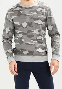 Sudadera gris de camuflaje con mangas largas, cuello redondo, puños y dobladillo acanalados, que presenta formas abstractas en gris claro sobre un fondo más oscuro.