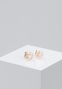 Orecchini circolari in oro rosa con design a stella intagliato, finitura lucida e chiusura a perno per una vestibilità sicura.