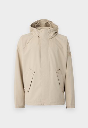 Chubasquero beige con capucha, que cuenta con dos bolsillos laterales, cierres de botón a presión y una tela texturada. Acabado con un pequeño logo en la manga.