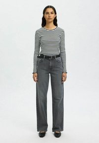 Schwarz-weiße gestreifte Langarmbluse kombiniert mit hoch taillierten, weiten grauen Jeans und schwarzen flachen Schuhen. Einfaches Design mit klassischer Passform.