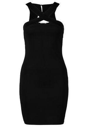 Femme portant une robe noire ajustée avec des bretelles croisées, des collants noirs translucides, des talons noirs et tenant une petite pochette rectangulaire.