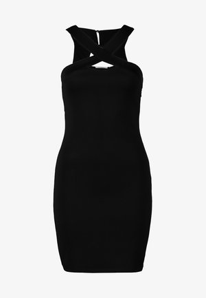 Mujer vestida con un vestido negro ajustado con tirantes cruzados, medias negras transparentes, tacones negros y sosteniendo un pequeño bolso de mano rectangular.