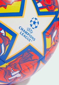 Palla da calcio con superficie testurizzata, con un audace design rosso e blu, una stella bianca centrale e il marchio della UEFA Champions League.