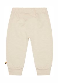 Beige katoenen broek met een elastische tailleband, opgerolde broekspijpen en een klein multikleurig label aan de zijkant. Zachte textuur, eenvoudig ontwerp.