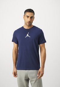 Tumed sinine puuvillane T-särk, millel on valge Air Jordan logo keskkrantil, ümarad kaelused ja lühikesed varrukad. Mugav lõige.