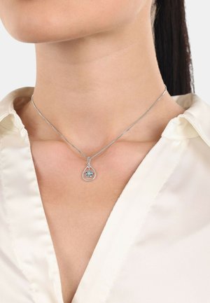 Collana in argento sterling con un pendente a goccia che presenta un design floreale in pietra blu, appesa a una sottile catena luminosa.