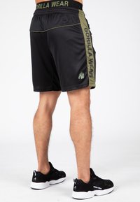 Pantaloni sportivi neri con pannelli laterali verde oliva e branding "GORILLA WEAR". Presentano una vita elastica e tasche con zip.