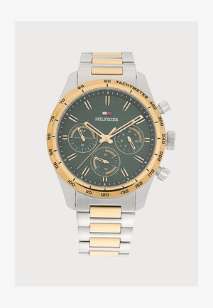 Montre-bracelet Tommy Hilfiger avec bracelet métallique or et argent, cadran vert foncé, trois sous-cadrans et échelle tachymétrique sur la lunette dorée.