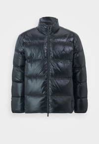 Chaqueta tipo puff de color negro, exterior acolchado brillante, cuello alto, cremallera frontal y detalle del logo en el pecho. Ligera, con una textura suave.