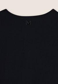 Top nero con scollo rotondo, texture liscia e piccolo dettaglio logo metallico sul retro. Design semplice e minimalista.