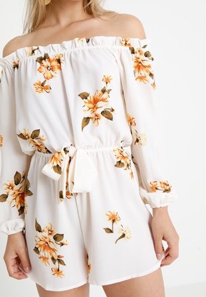 Valkoinen olkapäät paljastava haalari, jossa on pitkät hihat, oransseja kukkakuvioita, kiristysvyötärö ja sidottu vyötärönauha. Pehmeä kangas.