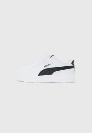 Baskets enfants blanches avec bande noire Puma, réglage Velcro et lacets sur un fond gris clair uni.