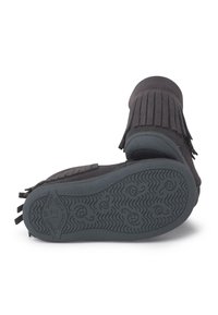 Zapatos estilo mocasín de ante negro con detalle de flecos, puntera redondeada y suelas de goma texturizadas con un patrón ondulado.