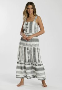 Vestido maxi blanco con patrones geométricos y florales en negro. Presenta tirantes ajustables, una cintura entallada y una falda acampanada.