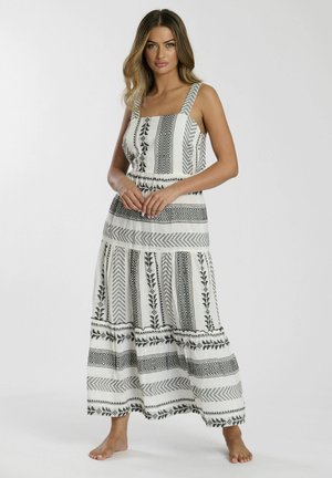 Witte maxi-jurk met zwarte geometrische en bloemmotieven. Heeft verstelbare schouderbandjes, een aansluitende taille en een uitlopende rok.
