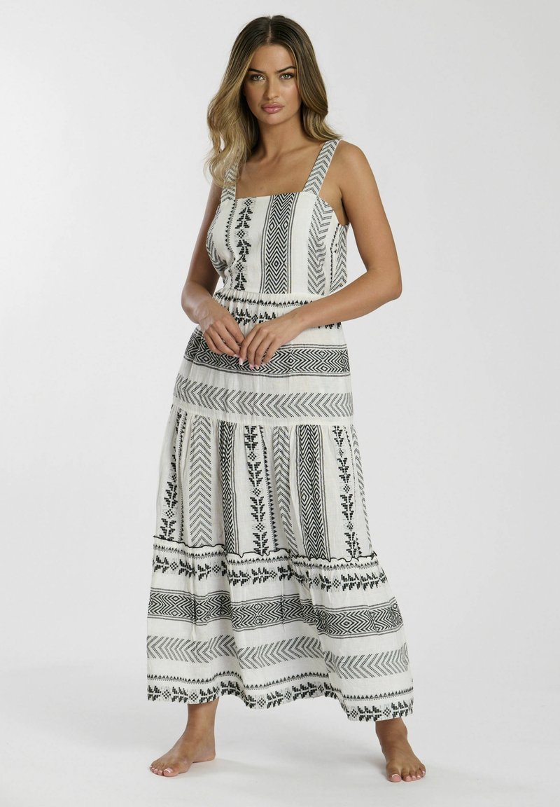 Vestido maxi blanco con patrones geométricos y florales en negro. Presenta tirantes ajustables, una cintura entallada y una falda acampanada.