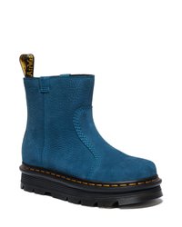 Bota de tornozelo azul em couro com acabamento texturizado, bico redondo e costura amarela. Apresenta uma sola de borracha preta e uma aba de puxar no calcanhar.