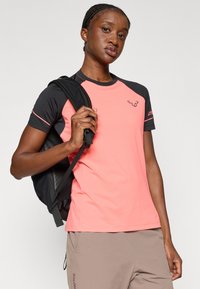 T-shirt atlético de mangas curtas em coral brilhante e preto, tecido que absorve a humidade, com decote redondo e detalhe do logo no peito.