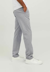 Šedé tepláky z měkké látky, s bočními kapsami, rovným střihem a jemnou texturou, kombinované s bílými teniskami.