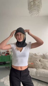 Musta neulottu balaclava-tyylinen huppu, jossa on ribbineulostekstuuri, istuva malli ja sileä viimeistely, jota käyttää henkilö vaaleassa yläosassa.