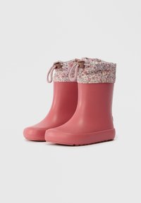 Ζευγάρι ροζ καουτσούκ γαλότσες με λουλουδάτες υφασμάτινες μανσέτες και κλείσιμο με σύρμα σε λευκό φόντο.