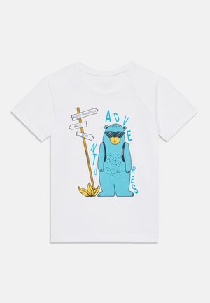 Witte katoenen T-shirt met een blauwe cartoonbeer met een zonnebril, naast een wegwijzer met richtingstekst in zwart en blauw.